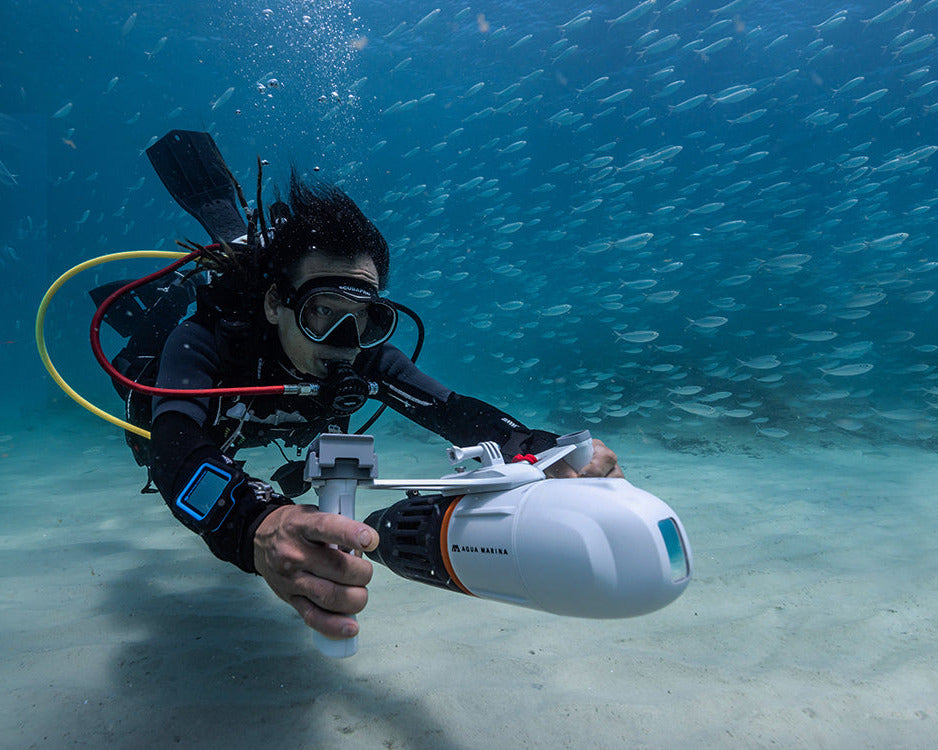 A diver underwater holding a white and blue water propulsion device labeled 'UNDERWATER JET'. The image features a dark blue background with white text reading 'WATER PROPULSION DEVICE' and a red underline.